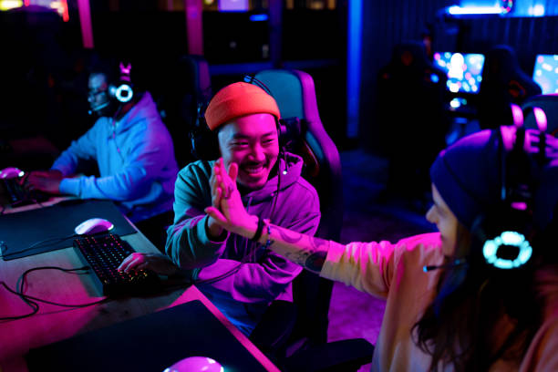 esports gamers high five team victory arena Esports gamers wearing headsets share a high five at their PCs in a neon-lit gaming arena after a successful match.