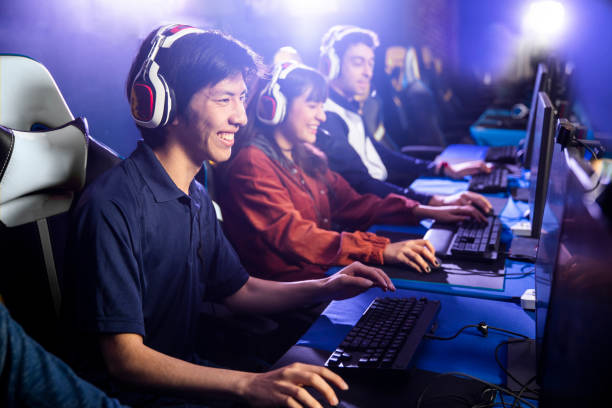 a team playing an esports game on a computer Esports team of young gamers wearing headsets and playing together on PCs in a competitive gaming tournament arena.